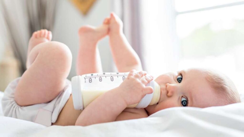 Un bebé disfrutando de un biberón de leche: La leche materna es el estándar de oro en nutrición infantil, proporcionando proteínas, grasas saludables, carbohidratos, vitaminas y minerales esenciales para el crecimiento.