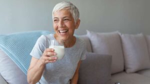 Una persona mayor disfruta de un vaso de leche, destacando cómo este alimento ayuda a prevenir la pérdida de masa ósea y muscular, crucial para un envejecimiento saludable.